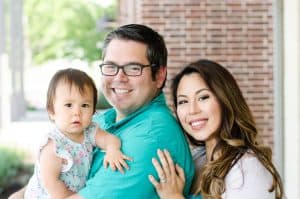 Smiling family portrait with a man, woman, and young child.