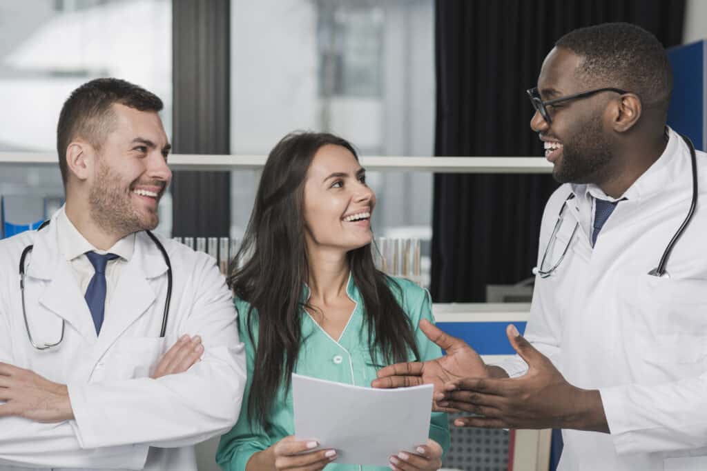 Group of smiling doctors and a nurse discussing medical documents.