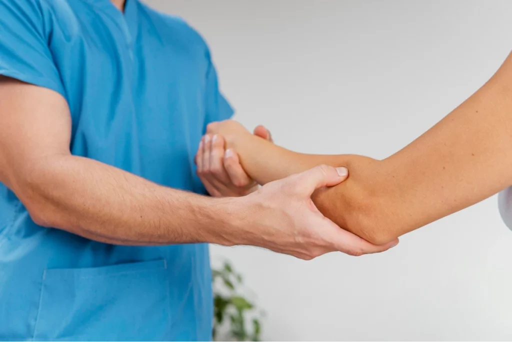 Healthcare professional examining a patient's arm during a physical assessment.