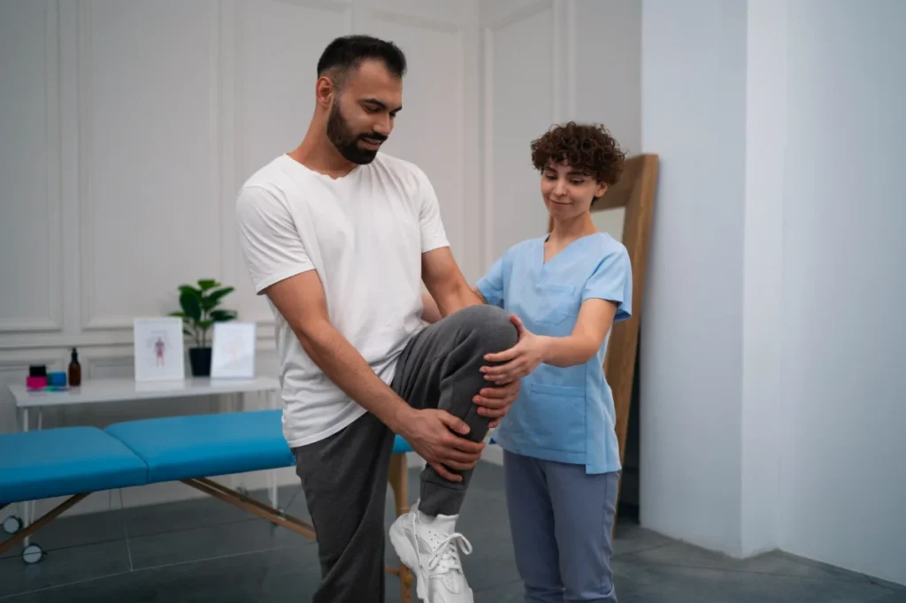 Dealing with Degenerative Arthritis 5 A physical therapist assisting a man in lifting his leg during a rehabilitation exercise in a clinical setting.
