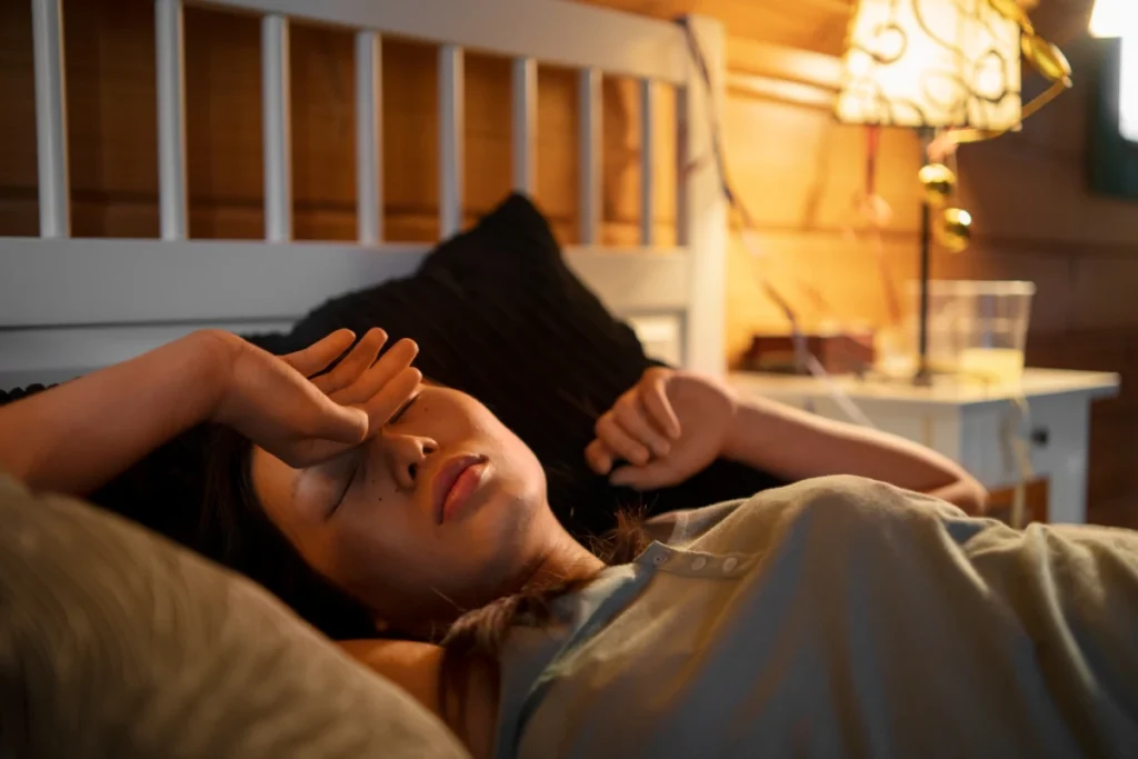 Woman lying in bed, appearing fatigued.