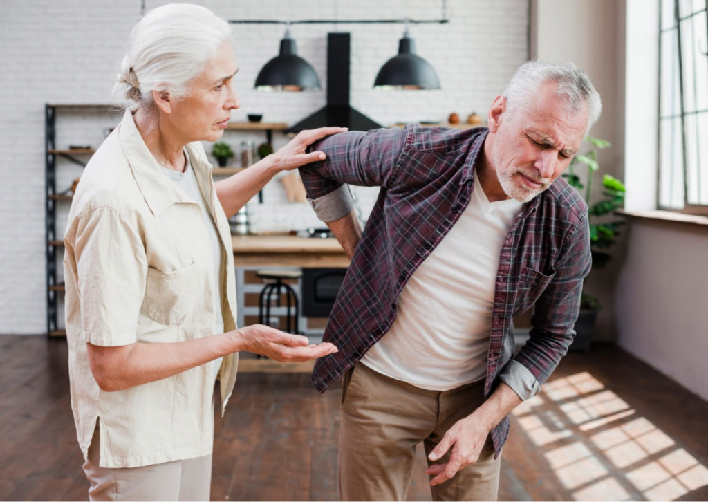 Elderly couple, with man suffering from back pain.