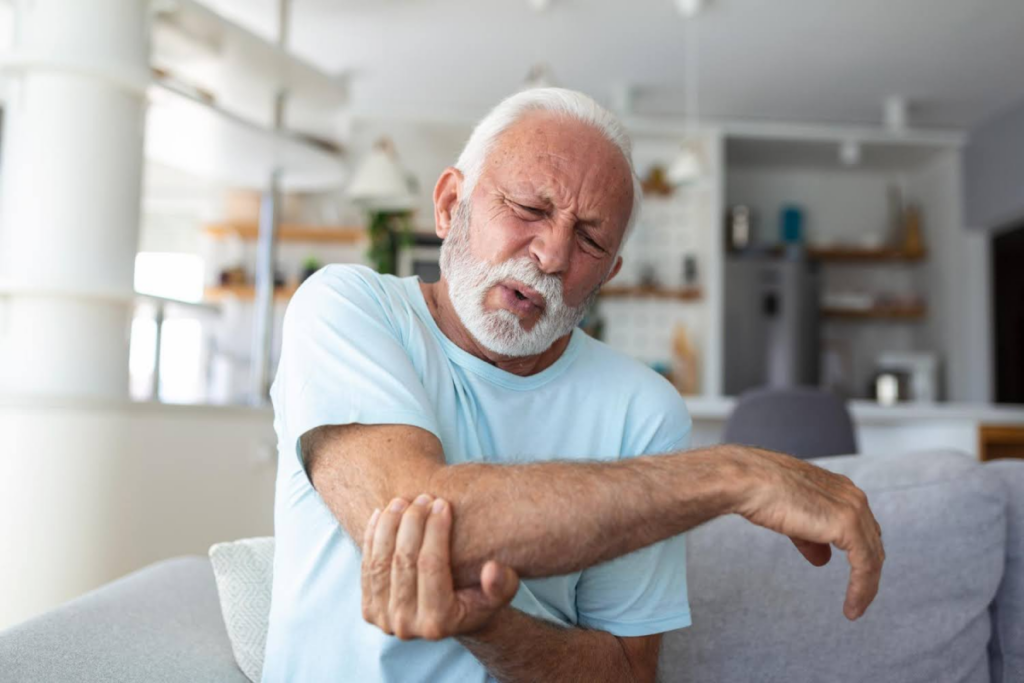 Elderly man massaging his elbow due to discomfort.