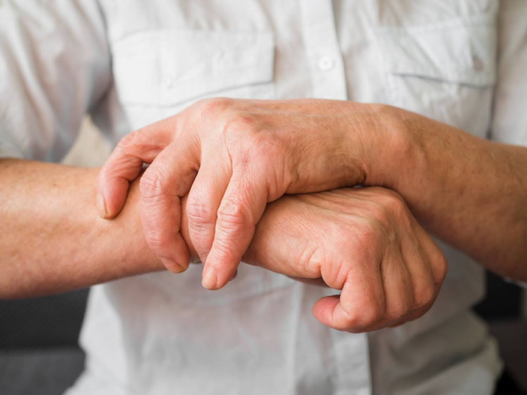 Person gripping their arm experiencing joint pain.