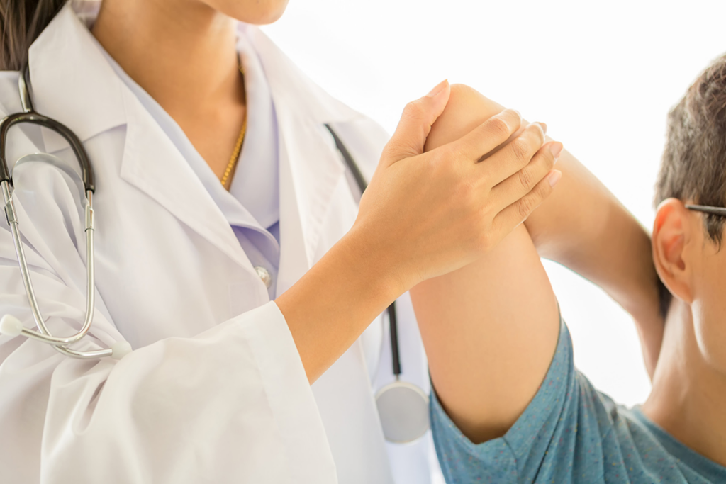 Orthopedic doctor examining a patient's elbow in a clinic setting.